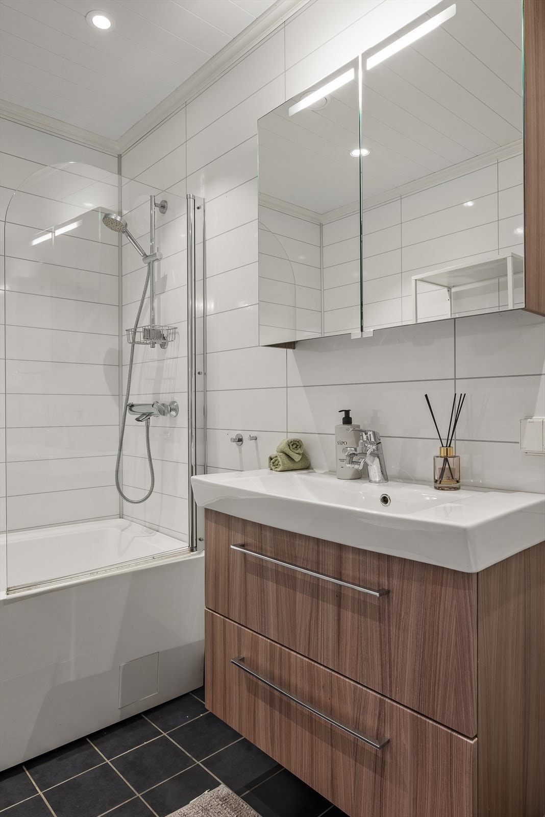 Badet har nøytrale fargetoner og gjennomført design. Innredning med skuffer og speilskap gir gode oppbevaringsmuligheter. I tillegg til badet byr boligen på et separat vaskerom. Galleribilde