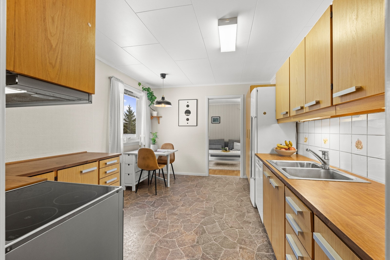 Innredningen er fra byggeår, med slette fronter og laminert benkeplate. Kjøkkenet har en funksjonell løsning med god benke- og skapplass. Galleribilde