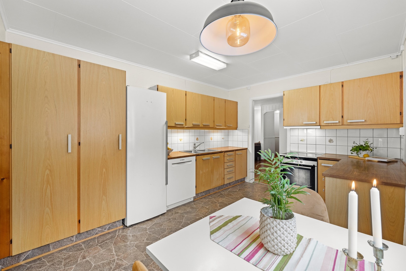 Kjøkkenet er utstyrt med frittstående kjøleskap, oppvaskmaskin og komfyr. Galleribilde