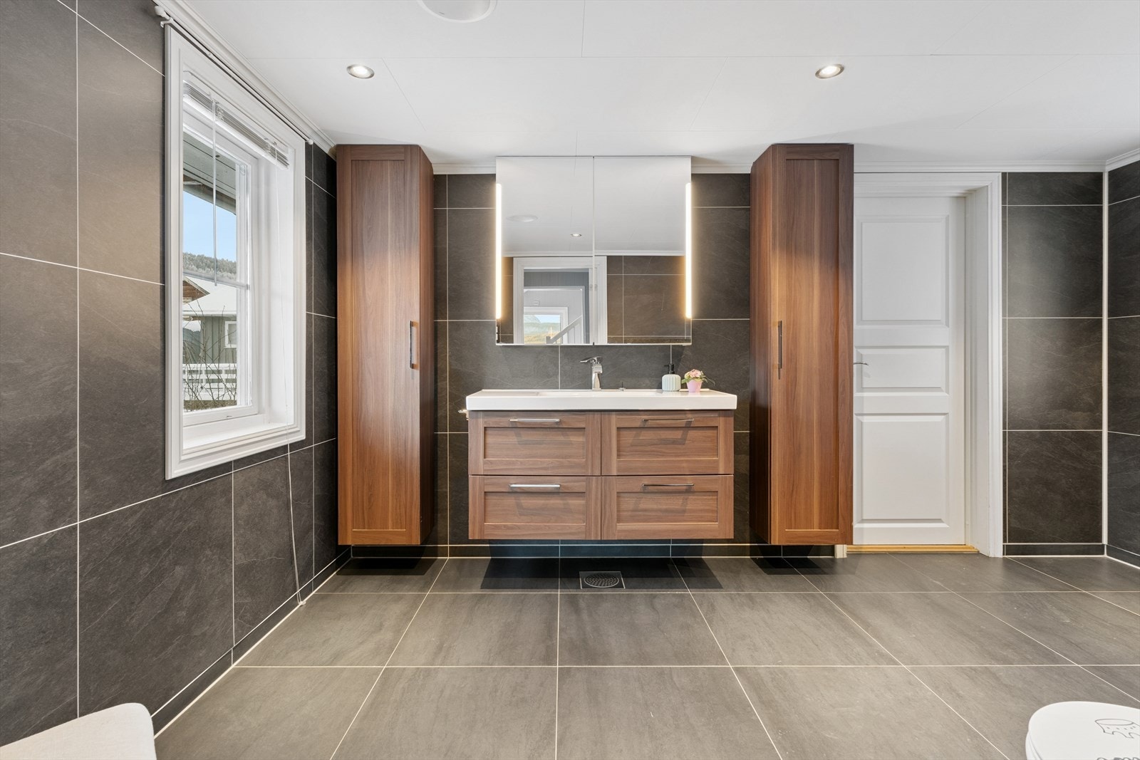 Baderomsinnredning med nedfelt servant og god oppbevaringsplass i høyskap. Galleribilde