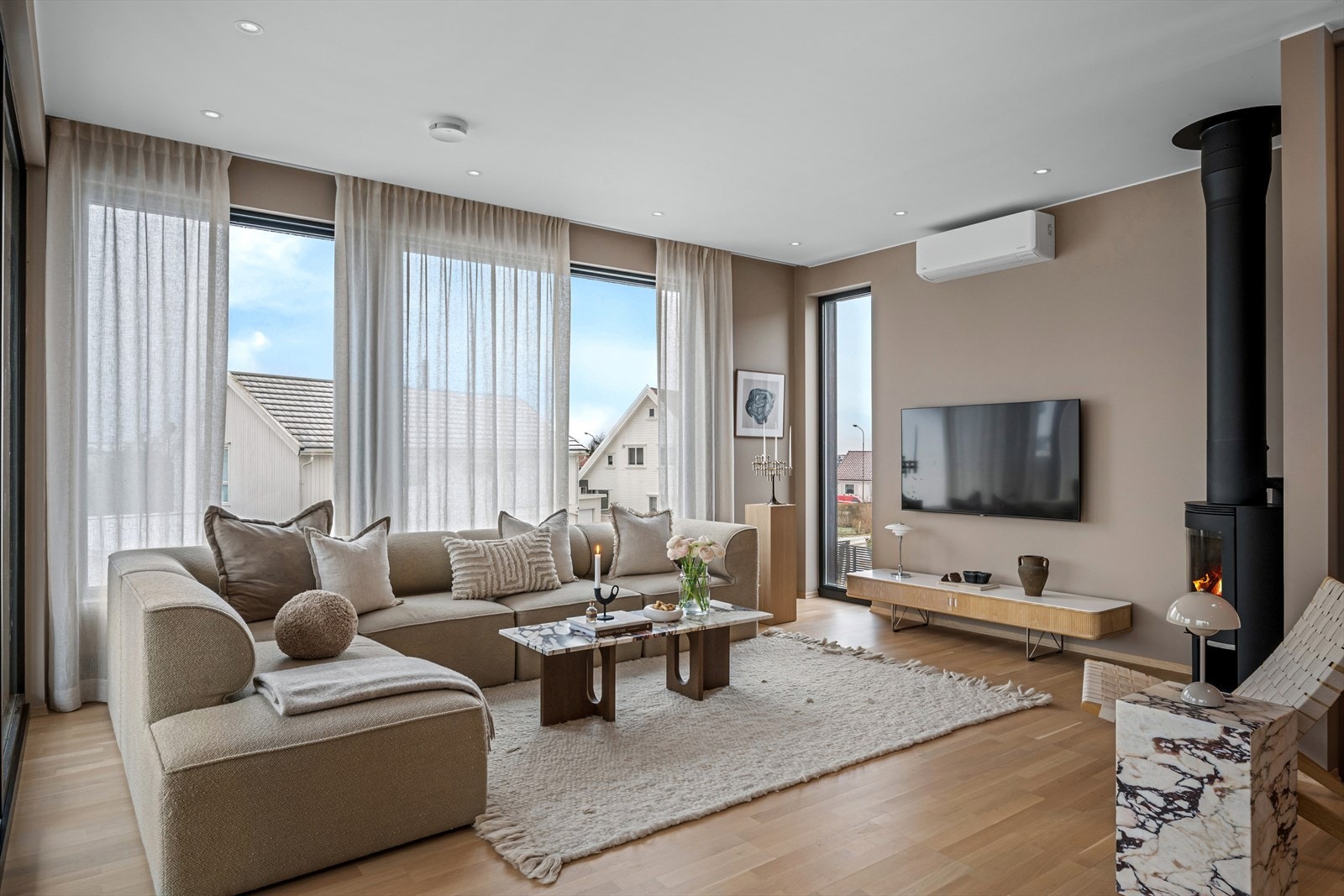 En herlig romfølelse med kombinasjonen av store vinduer og naturlig lys, peisovn for ekstra varme og atmosfære, samt naturlige soner for møblering. Galleribilde