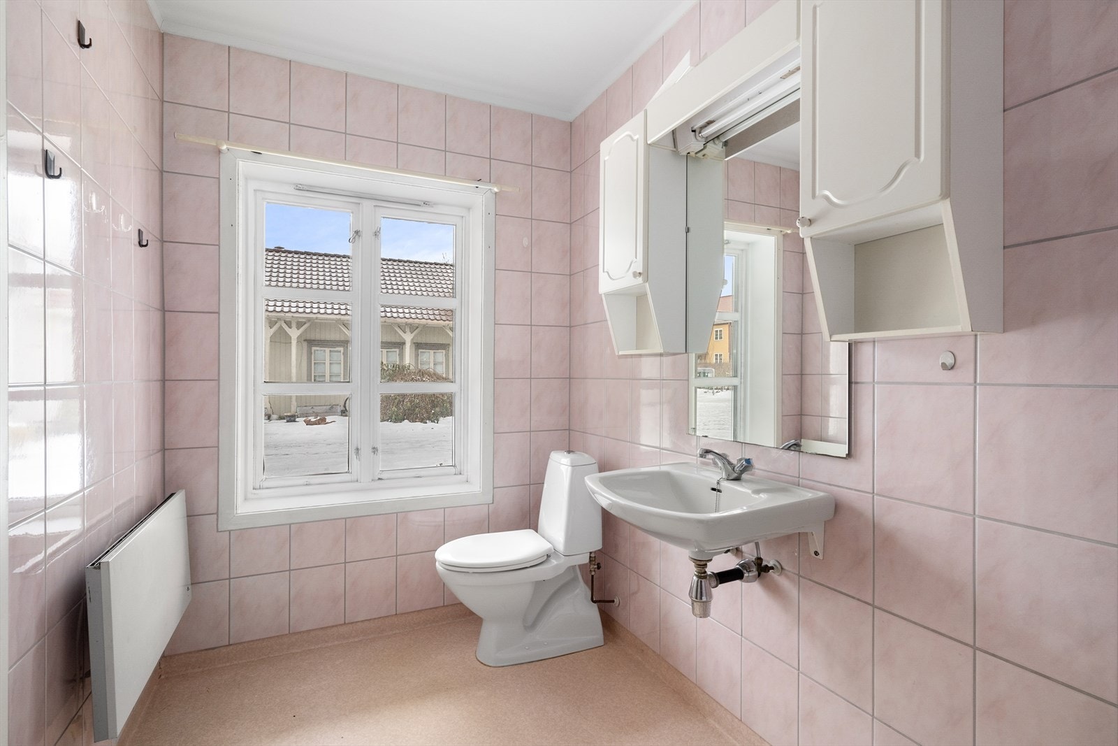 Baderommet er av eldre dato og inneholder badekar med dusj, servant, overskap med lys, speil og gulvmontert toalett. Galleribilde