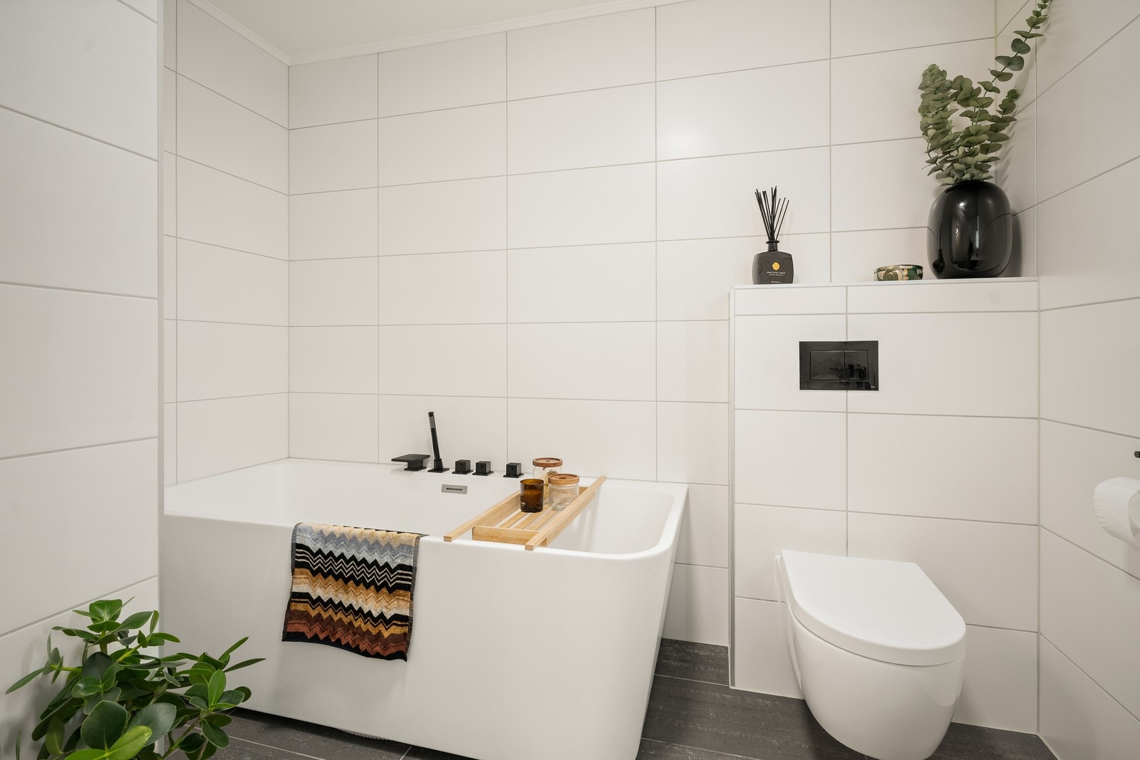 Badet er utstyrt med vegghengt toalett, badekar, samt baderomsinnredning med dobbel servant og speil. Galleribilde