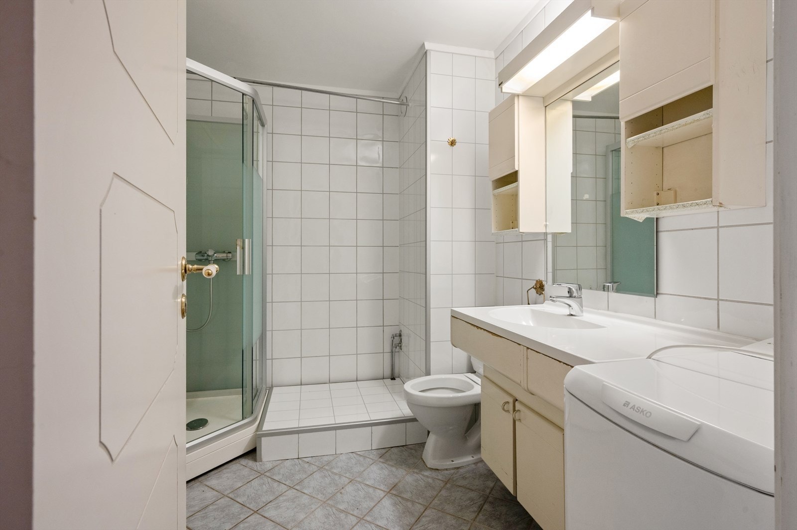 Baderom med dusjkabinett, servant med speilskap og toalett. Galleribilde