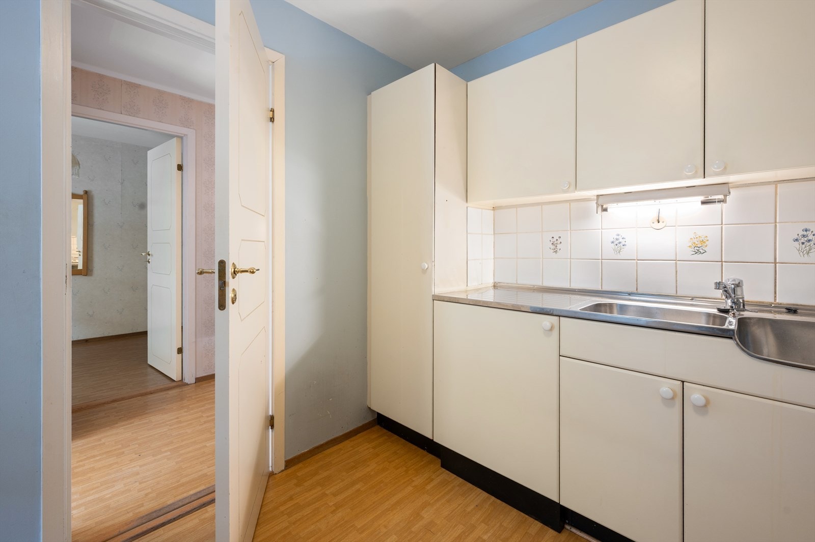 Kjøkkenkrok med eldre skapfronter og fliser mellom benk og overskap. Galleribilde