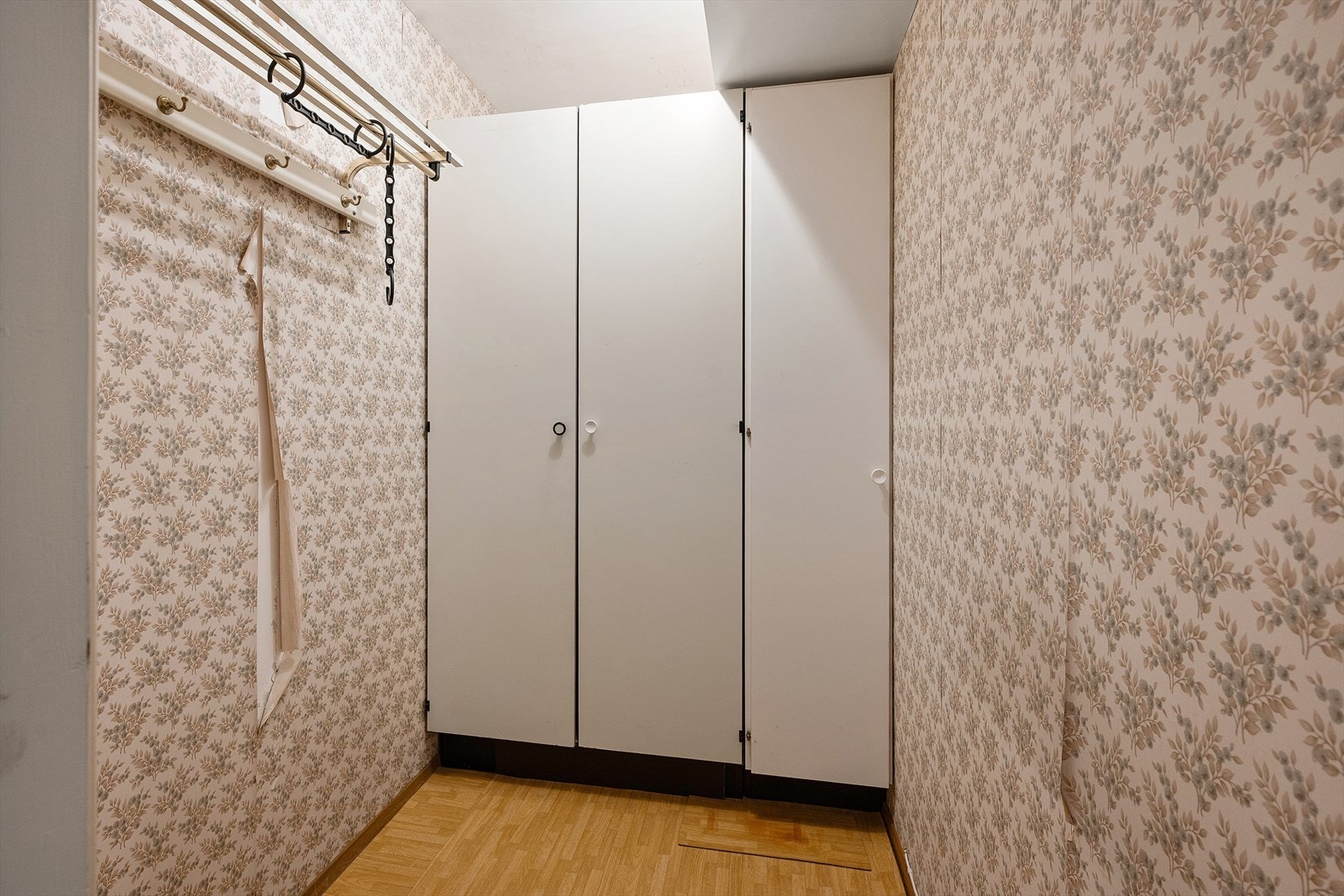 Praktisk innvendig bod med veggskap og knaggrekke - tapet og gulv er slitte og trenger oppussing Galleribilde