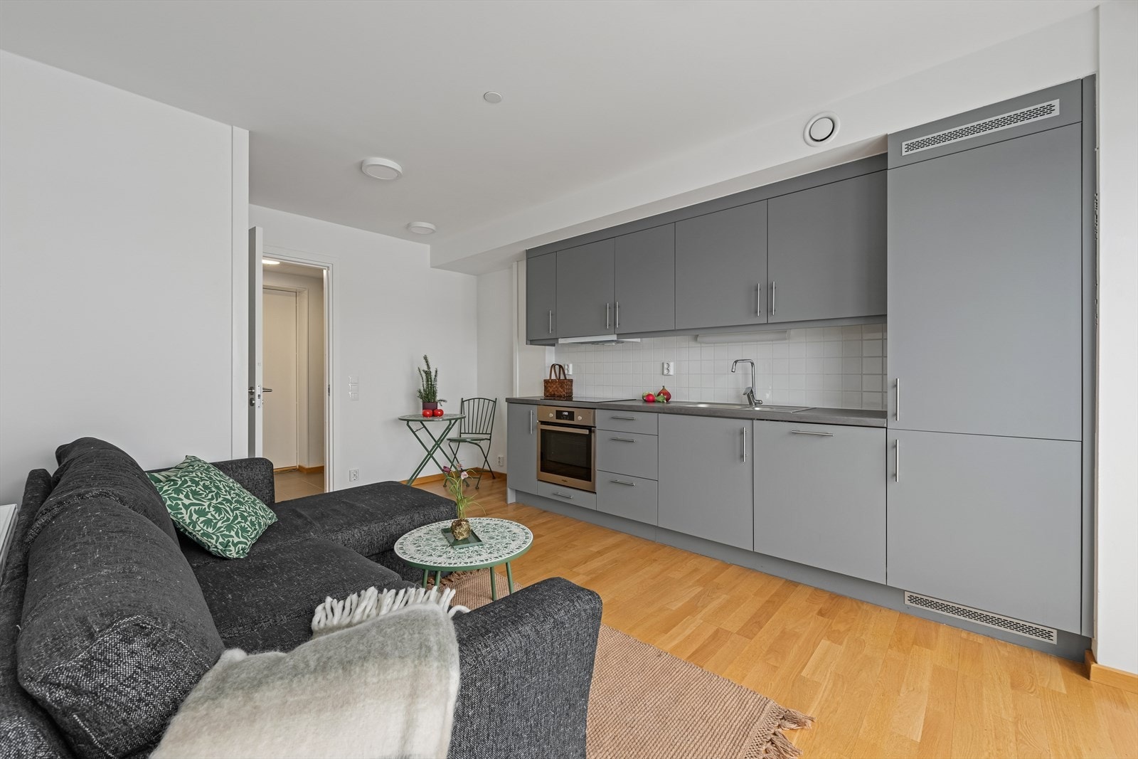 Kjøkkenet har en moderne innredning med glatte fronter og en benkeplate i laminat med oppvaskkum av stål. Galleribilde