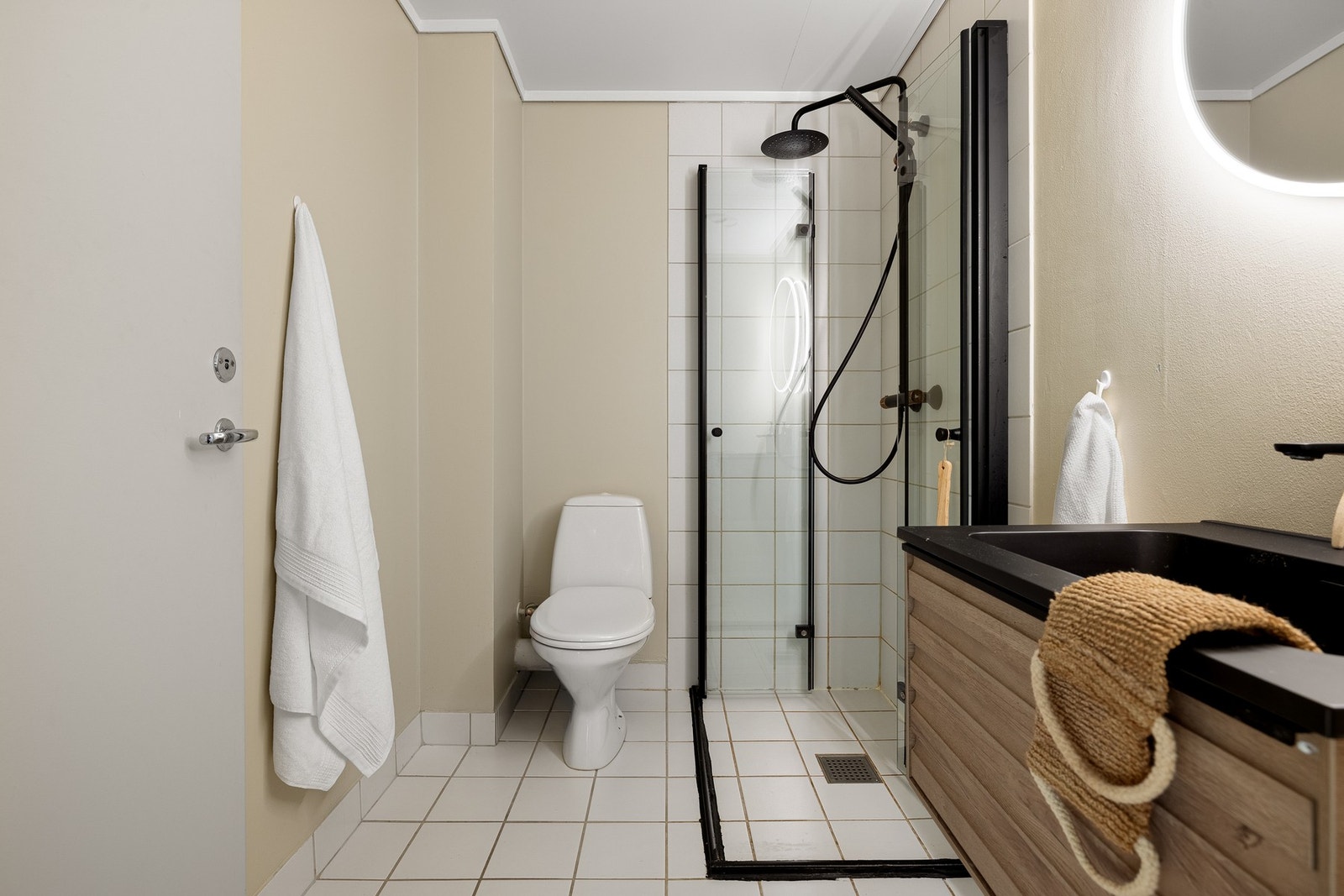 Badet måles til 3,5 kvm. og er fliselagt på gulv med underliggende varmekabler. Veggene er delvis flislagt og delvis kledd med slett malt platekledning Galleribilde