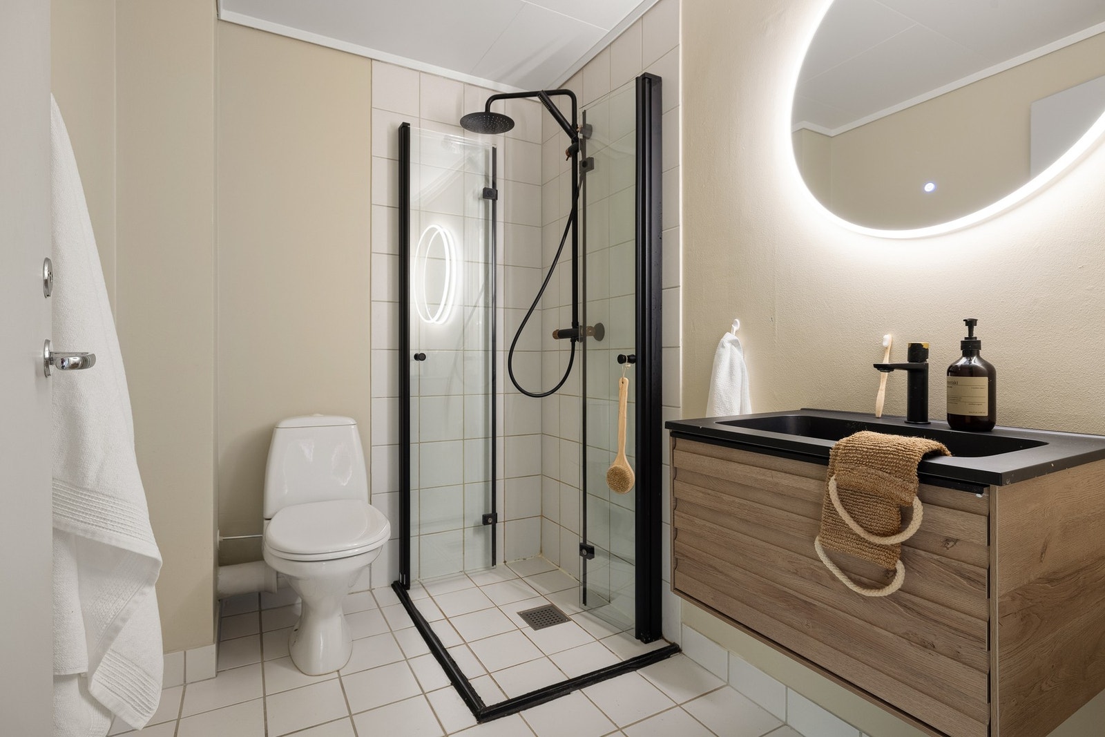 Badet er innredet med toalett, dusj med glassvegger samt baderomsinnredning med servant, speil og belysning. Galleribilde