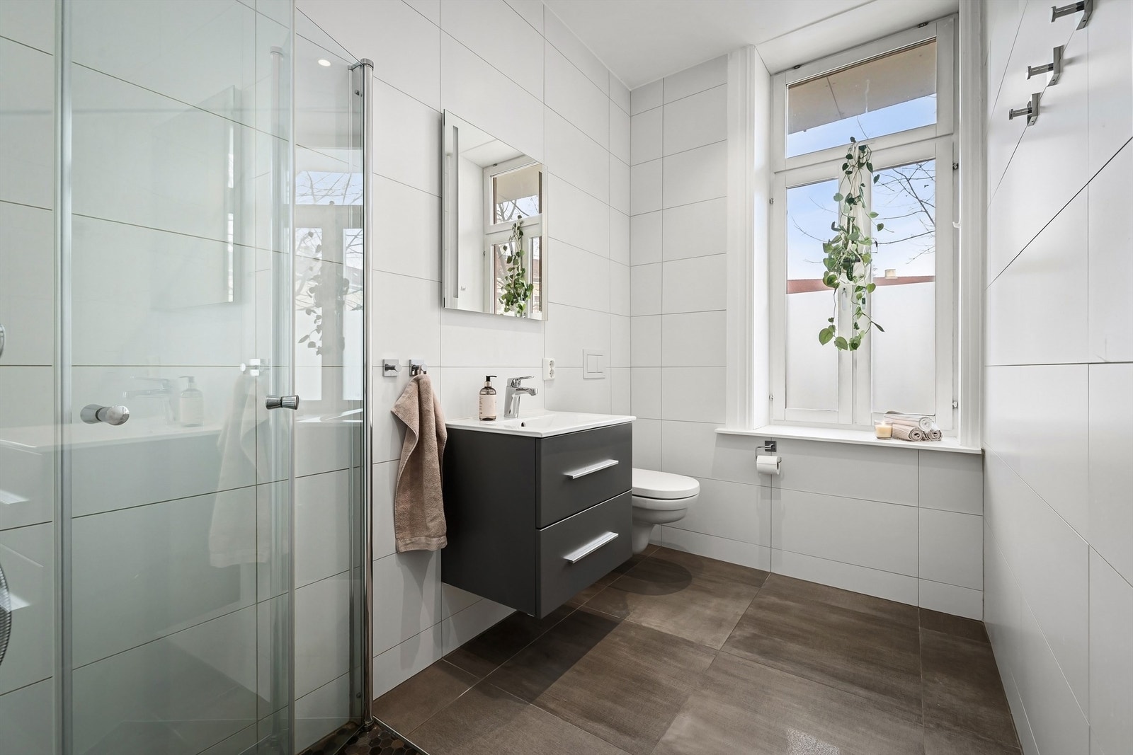 Delikat flislagt baderom pusset opp i 2020 med gulvvarme og downlights. Vegghengt servantskap med skuffer, ovenpåliggende servant og speil over med integrert lys Galleribilde