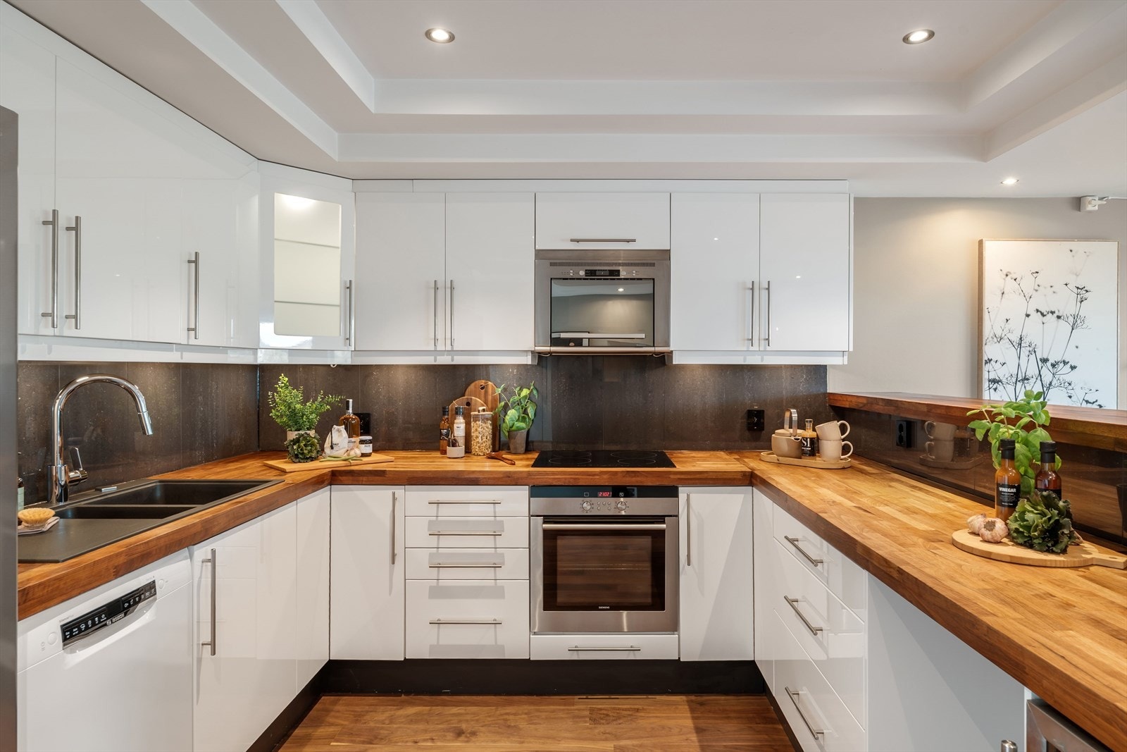 Lyst og innholdsrikt kjøkken med godt med benke- og skapplass Galleribilde