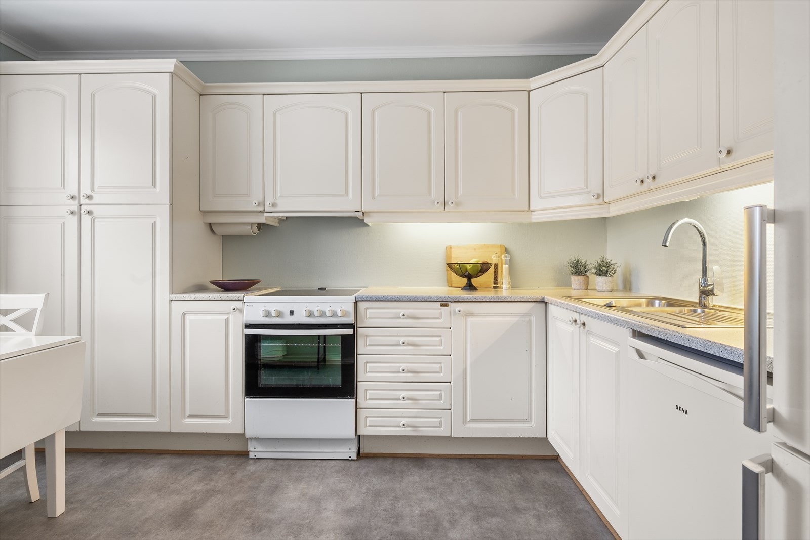 Kjøkkenet fremstår lyst, pent og innbydende, med en praktisk utforming som gjør det både funksjonelt og trivelig å oppholde seg i. Galleribilde