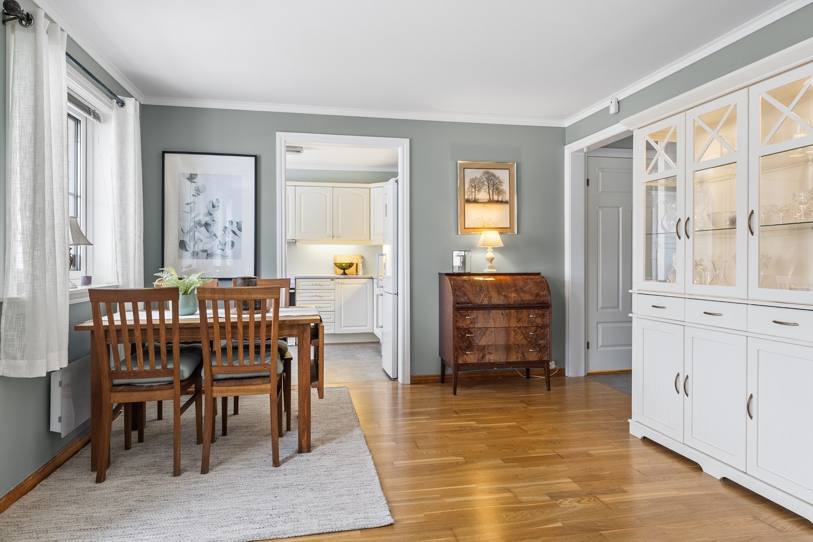 Veggene er malt i en smakfull og harmonisk fargetone som gir rommet en lun, men samtidig moderne atmosfære. På gulvet ligger en tidsriktig trestavs eikeparkett som tilfører varme og et helhetlig, stilrent uttrykk. Galleribilde