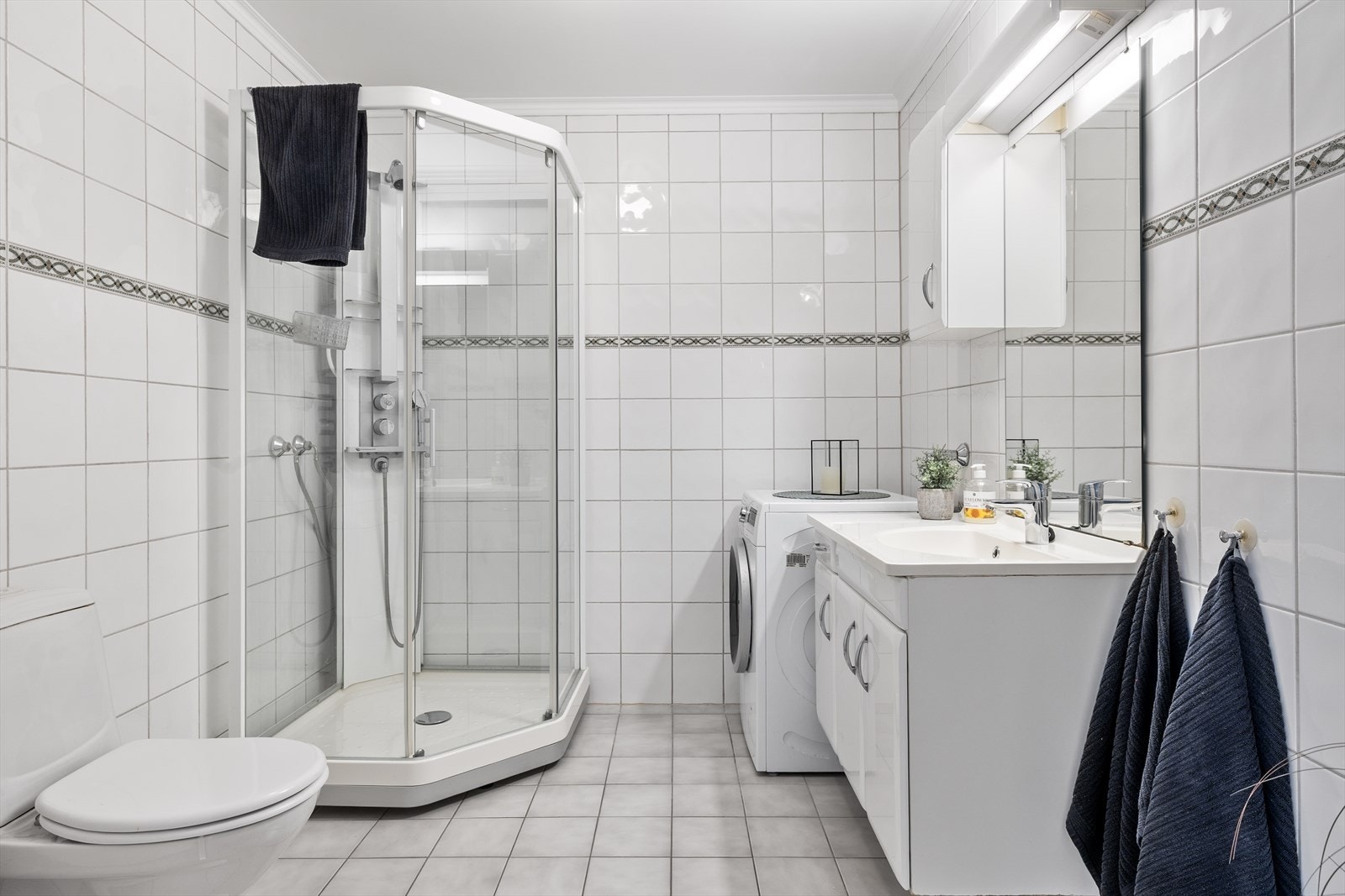 Badet fremstår som helhetlig og funksjonelt innredet med pene materialvalg og gjennomtenkte løsninger. Gulvet er flislagt og utstyrt med behagelige varmekabler som sørger for lun komfort året rundt. Galleribilde