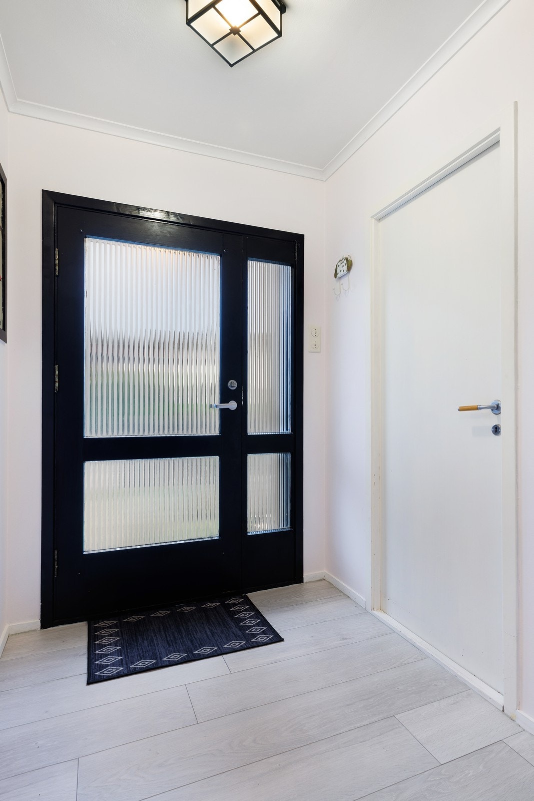 Lys og åpent inngangsparti med nymalte overflater og laminat på gulv. Galleribilde