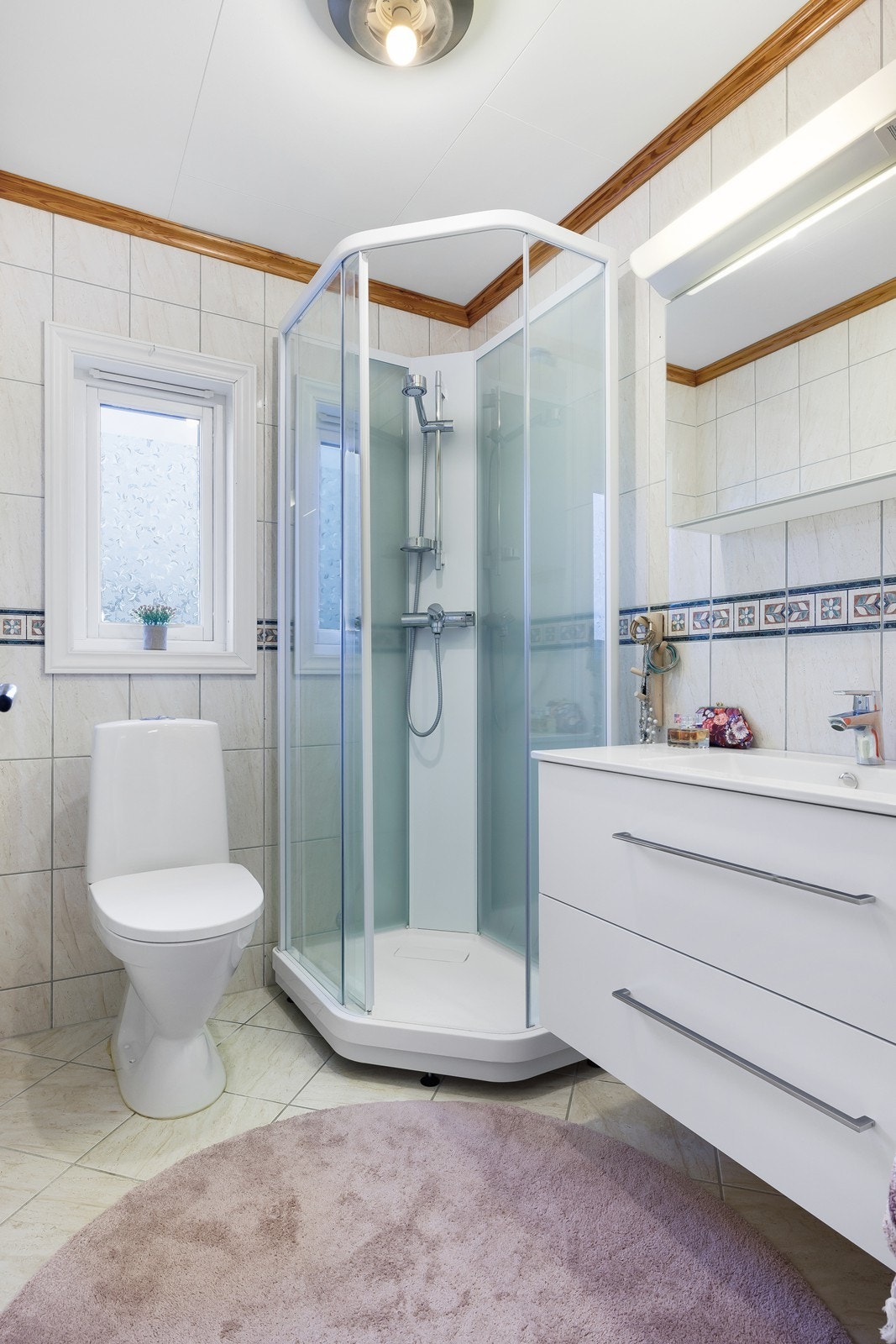 Lyst helfliset baderom med dusj, toalett og servant med tilhørende skuffer. Satt inn nytt dusjkabinett og servant i 2025. Galleribilde