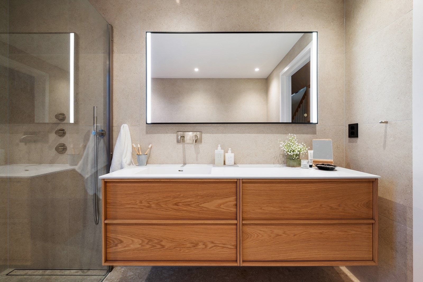 Badet har vask med benkeplate og servant i Corian, servantskap og benkeskap fra Korsbakken Bad samt speil av modell Nyborg på 75X140 med lys. Kraner er innebygget og har detaljer er i børstet stål, inkludert Silhouet servantkran og toalettrullholder. Galleribilde