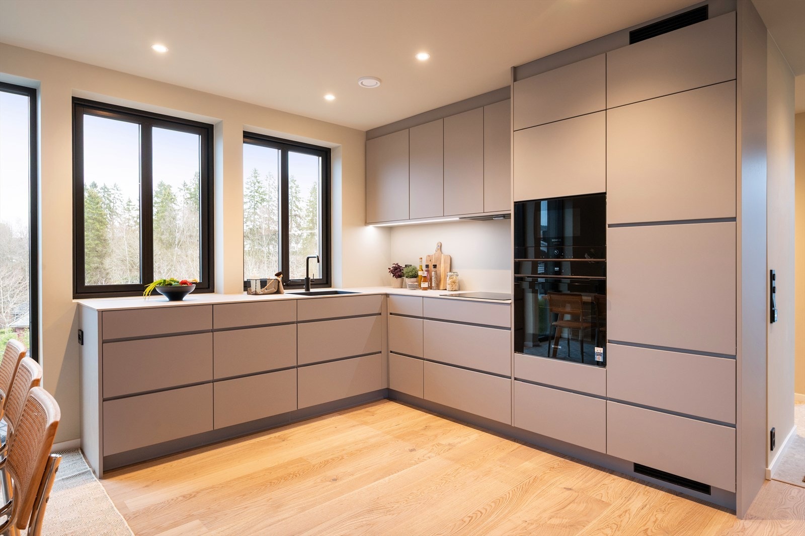 Håndtaksfrie fronter og sokler i samme utførelse gir et helhetlig og elegant preg. Benkeplaten i lys grå laminat (Light Grey Bellisara) er slitesterk og praktisk, med underlimt vask for en ren og moderne linje. Galleribilde