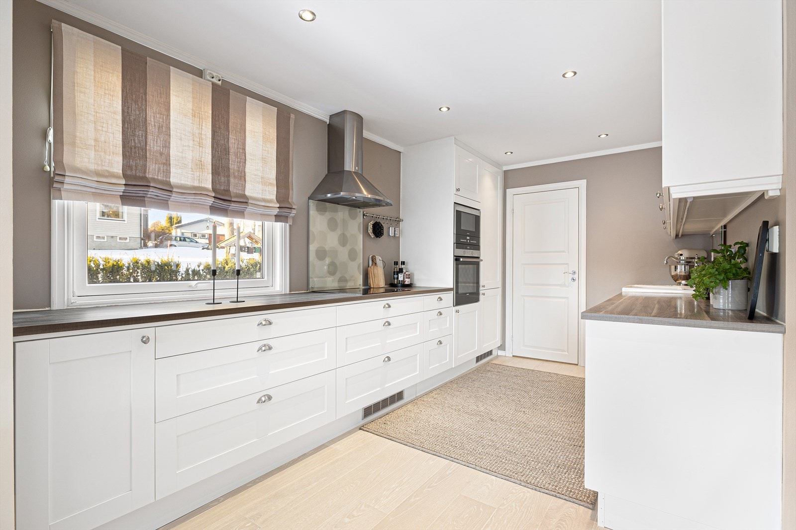 Kjøkkenet fremstår moderne og innbydende, kombinert med et stilrent glassfelt over benken som gir et lettstelt preg. Galleribilde