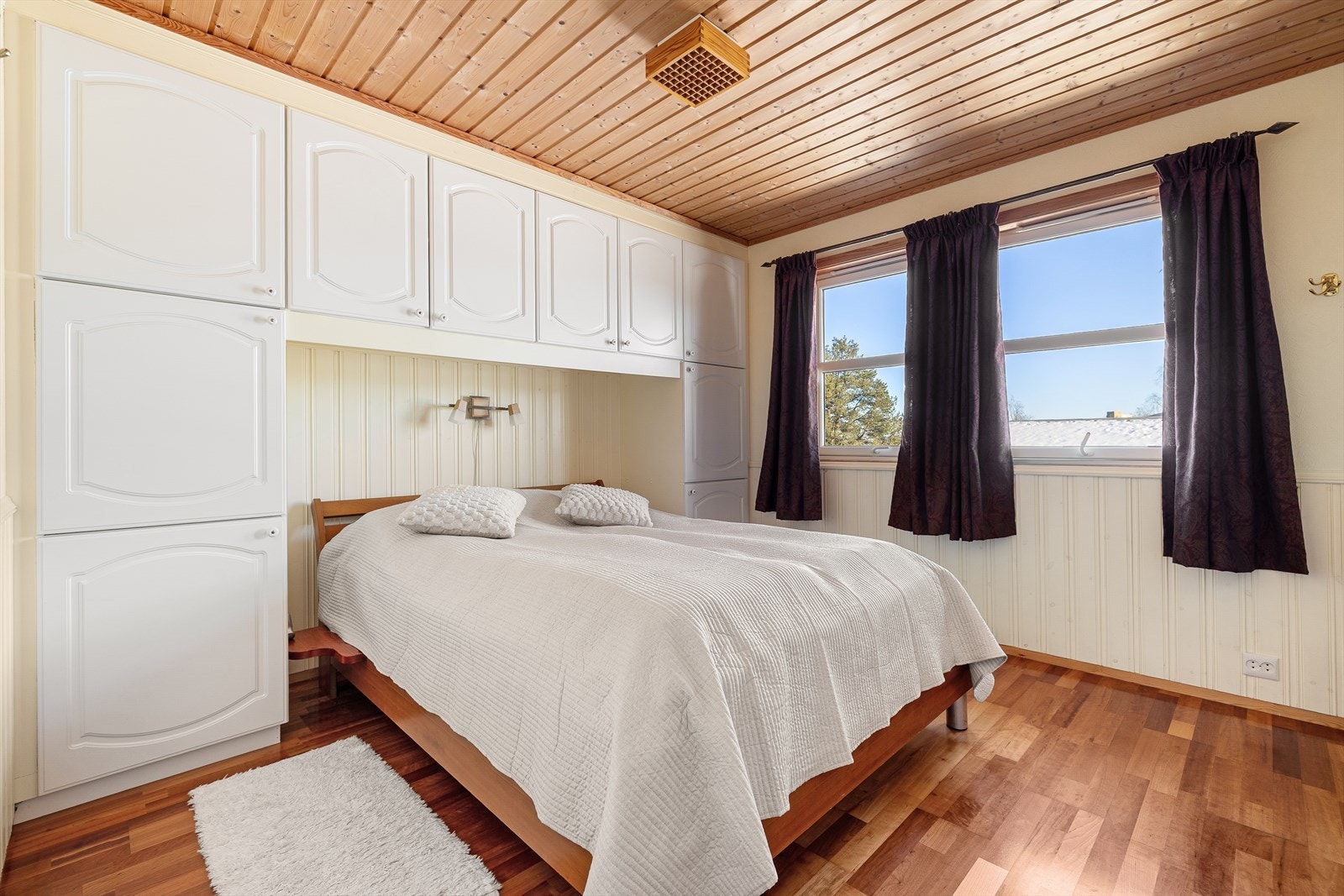 Lyst og trivelig rom på 12 m². Rommet har parkett på gulvet og malt panel med brystpanel på veggene. Galleribilde