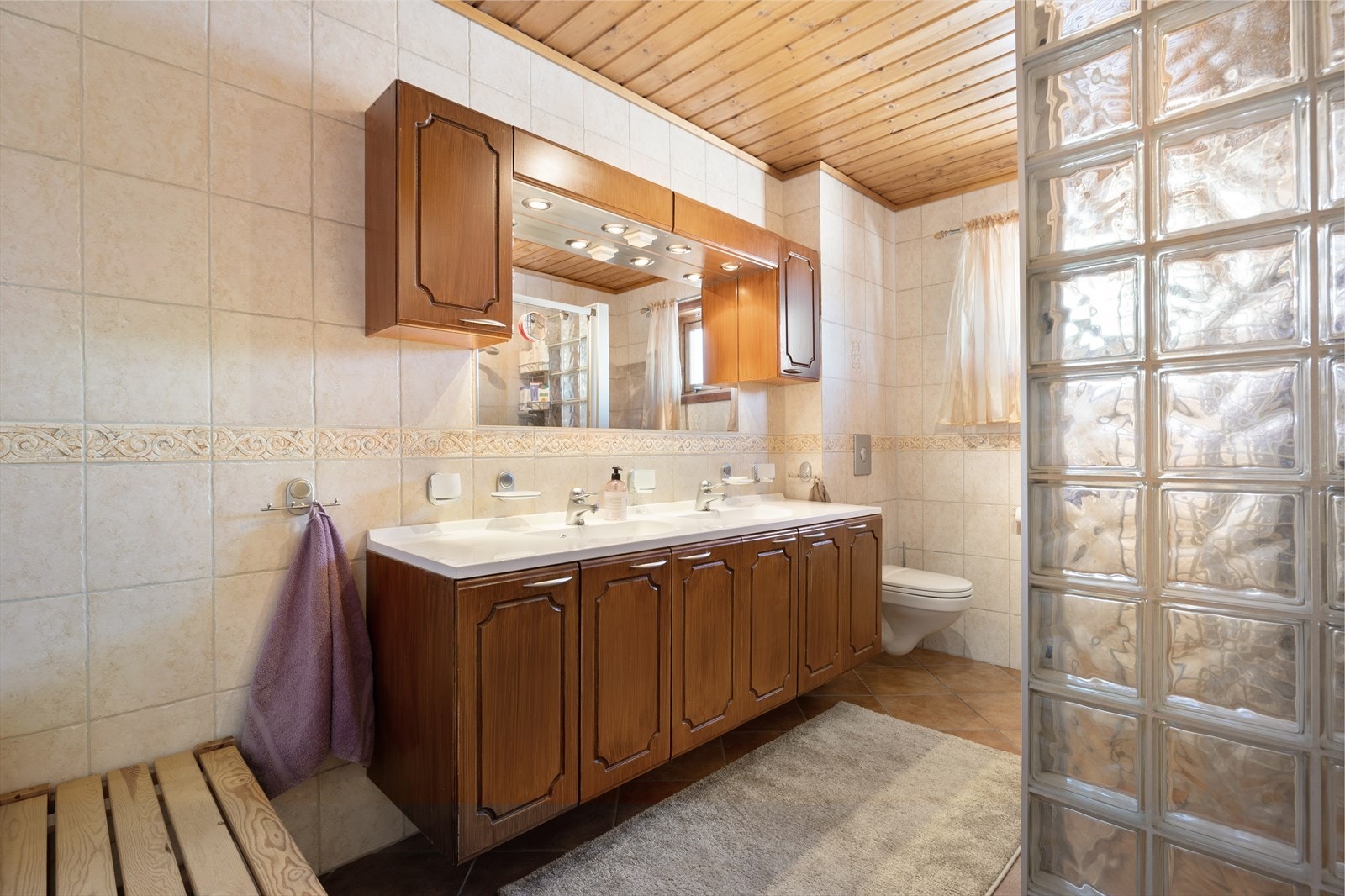 Badet har flislagt gulv og flislagte vegger, med panel i himling og gulvvarme. Galleribilde