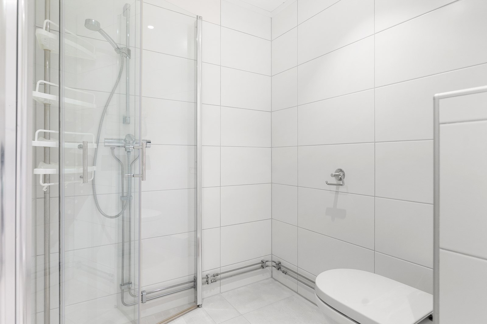 Praktisk bad med dusjhjørne, toalett, baderomsinnredning, opplegg for vaskemaskin og varmekabler i gulv Galleribilde