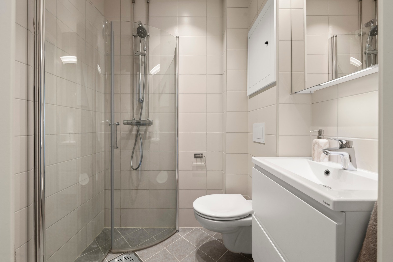 Badet er et stilrent og flislagt baderom fra 2019, med behagelig gulvvarme Galleribilde