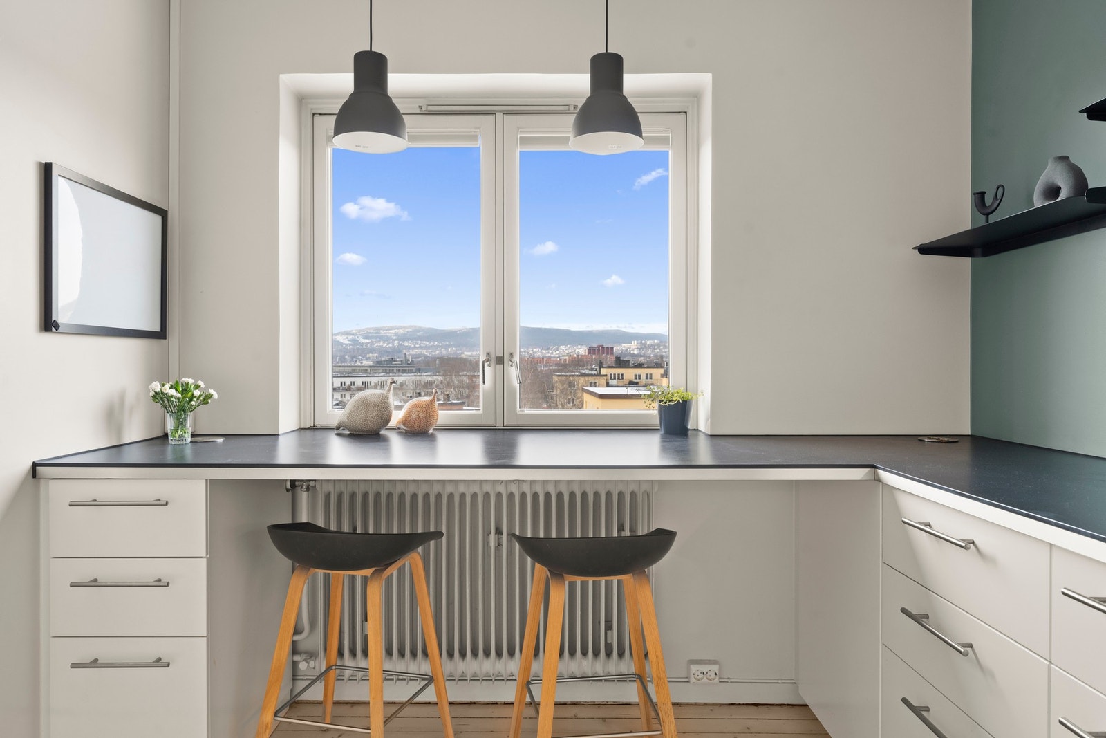 Store vindusflater sørger for godt med naturlig lys, og kjøkkenet har plass til barstoler - et hyggelig sted å nyte morgenkaffen Galleribilde