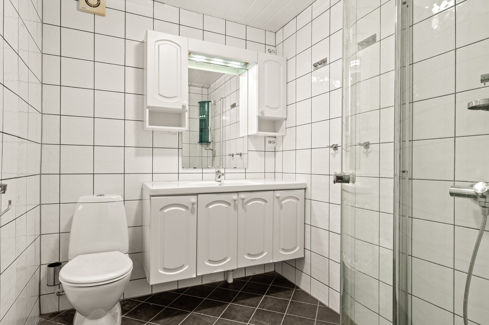 Etasjens bad er helfliset og utstyrt med dusjhjørne og servant med oppbevaring. Galleribilde