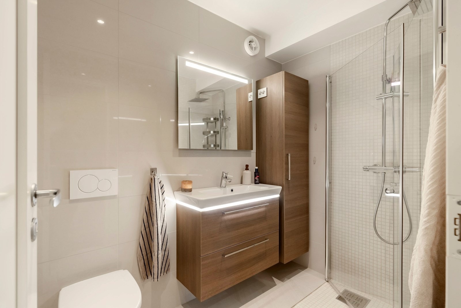 Lekkert bad med varmekabler i gulv, innfellbare dusjvegger, vegghengt WC og god plass i baderomsinnredning. Det er etablert baderomsvifte. Galleribilde