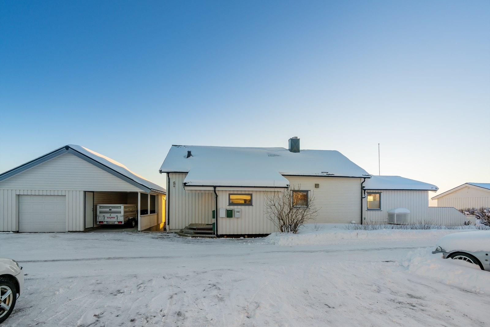 Fint opparbeidet forside av eiendommen, med garasje og carport Galleribilde