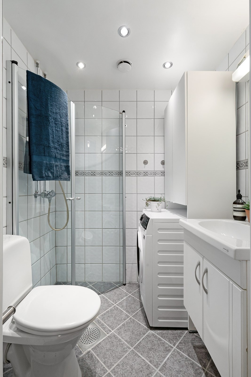 Pent flislagt baderom med varme i gulvet. Innredet med gulvstående toalett, servant med underskap, speil, dusjhjørne med innfellbare dører og opplegg til vaskemaskin. Galleribilde