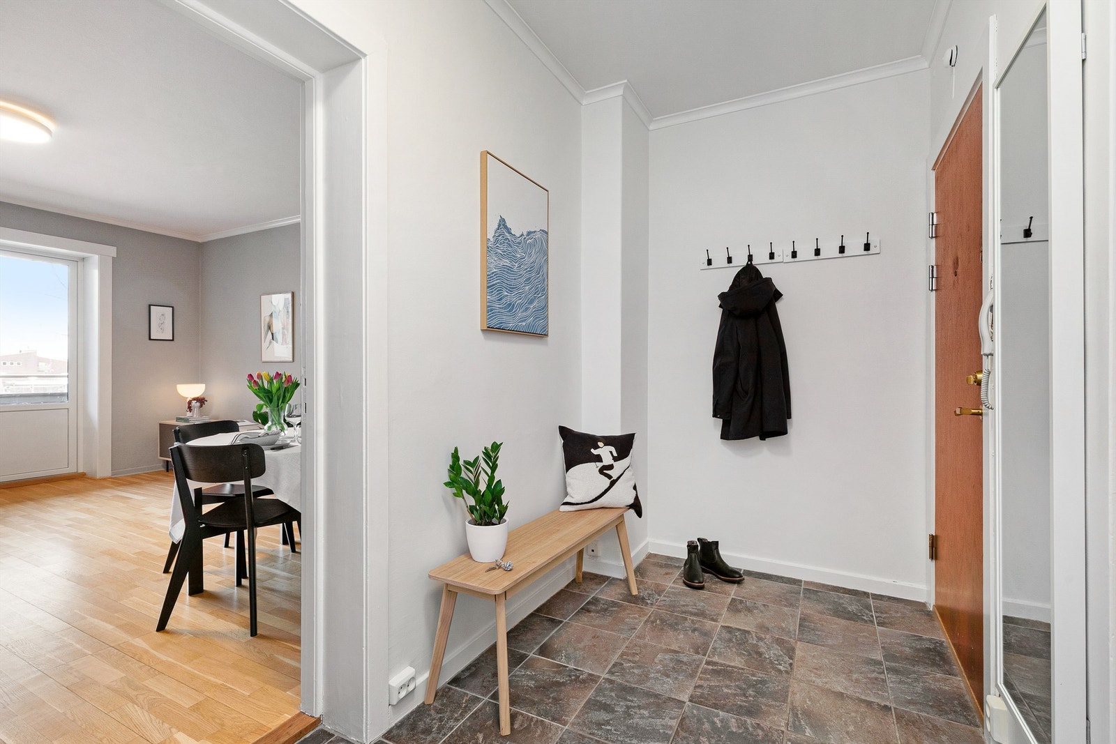 Lys entré med flislagt gulv. Her er det plass til å henge fra yttertøy på vegghengte knagger samt plass til en sittebenk eller hylle/garderobeskap. Galleribilde