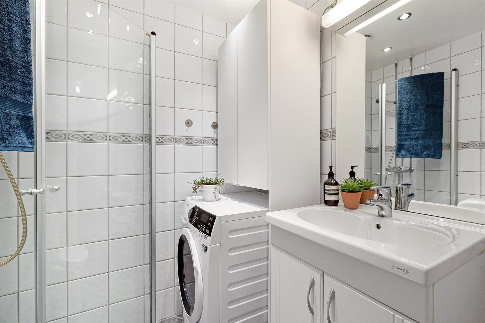 Praktisk skap over vaskemaskin med ekstra oppbevaringsplass. Borettslaget har også et felles vaskeri i underetasjen. Galleribilde