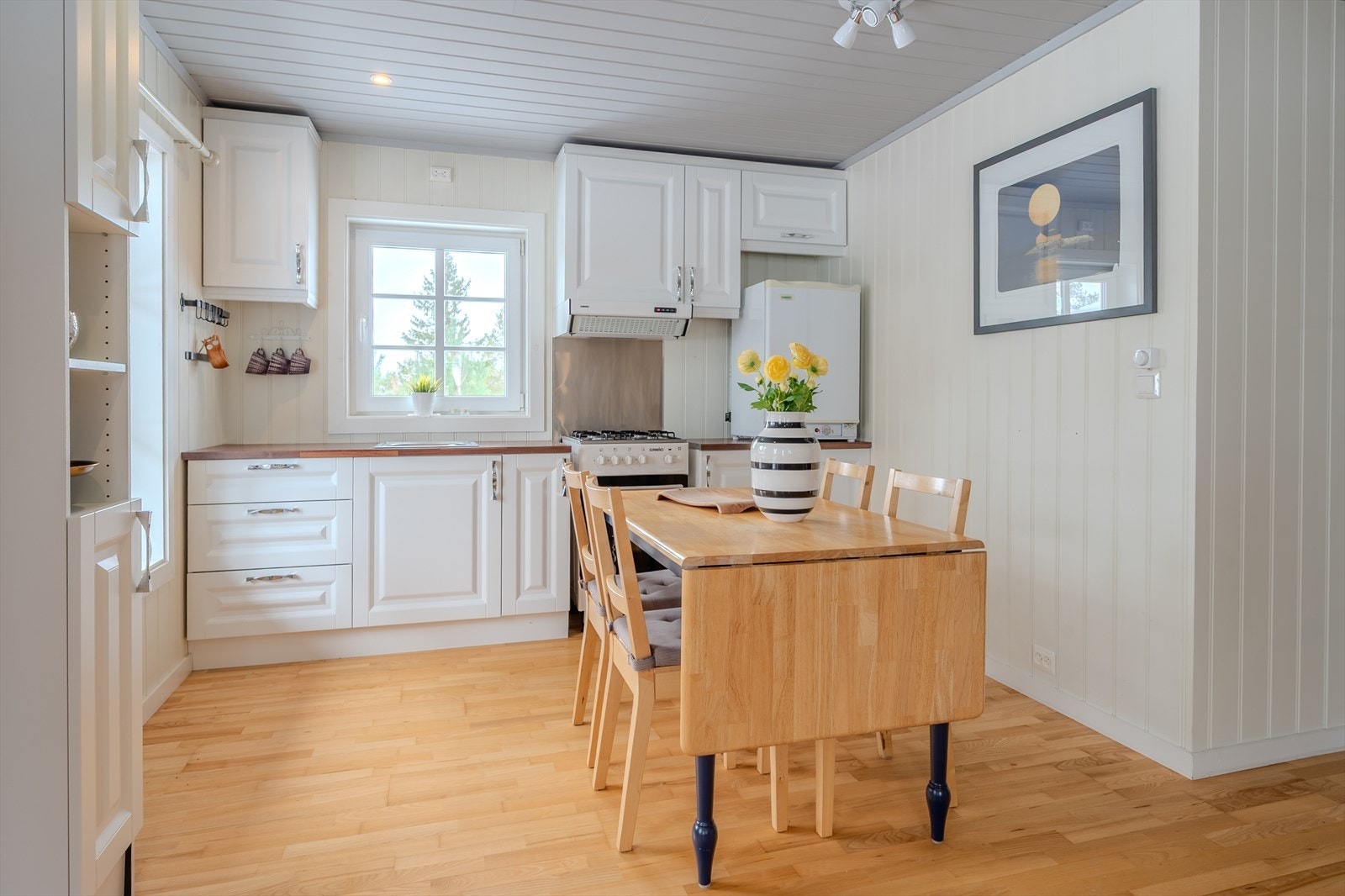 Klassisk kjøkken med profilerte fronter, laminert benkeplate og plate i børstet stål bak komfyr Galleribilde