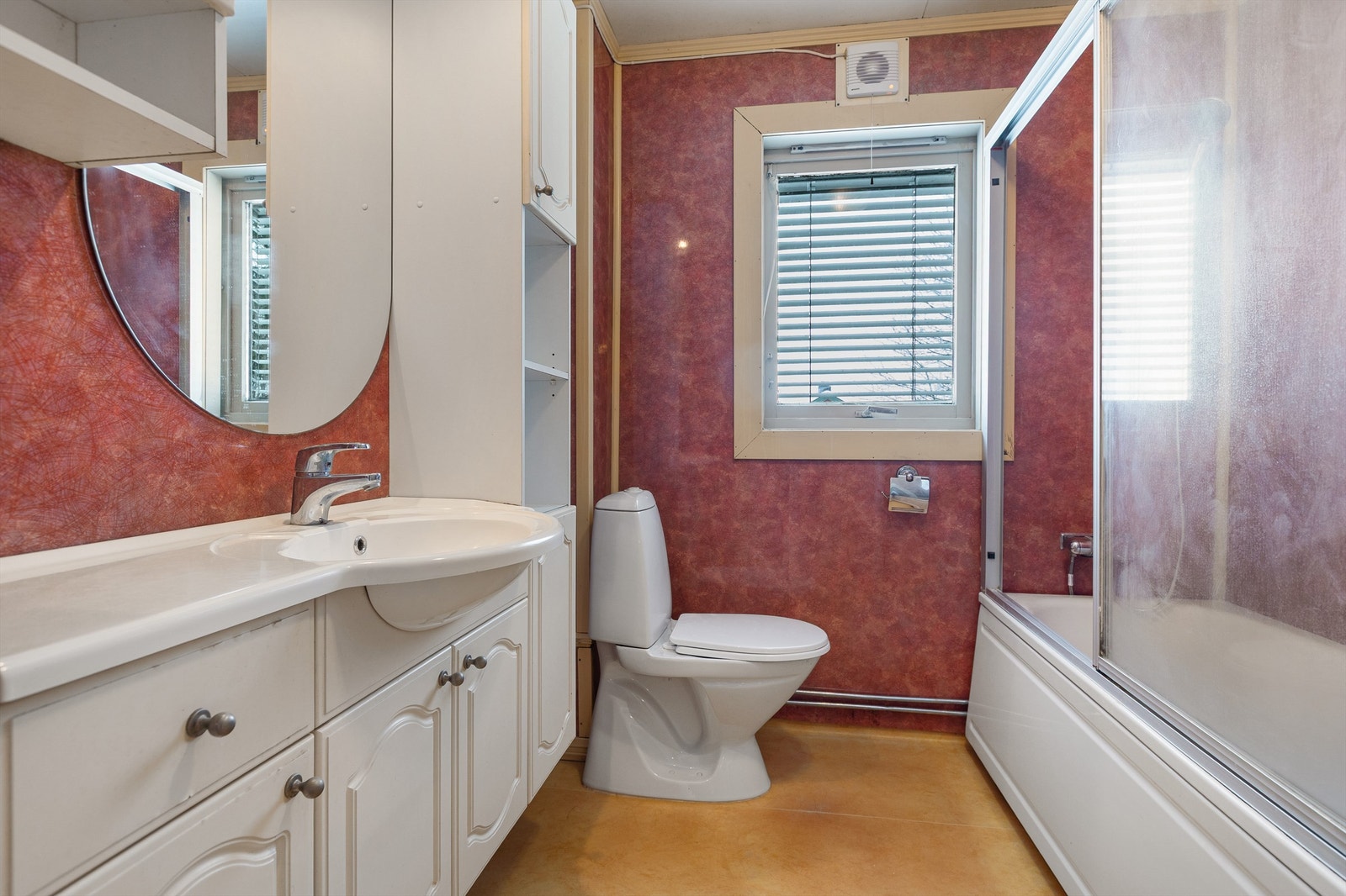 Bad med badekar innredning med nedfelt servant, gulvstående toalett og opplegg for vaskemaskin. Galleribilde