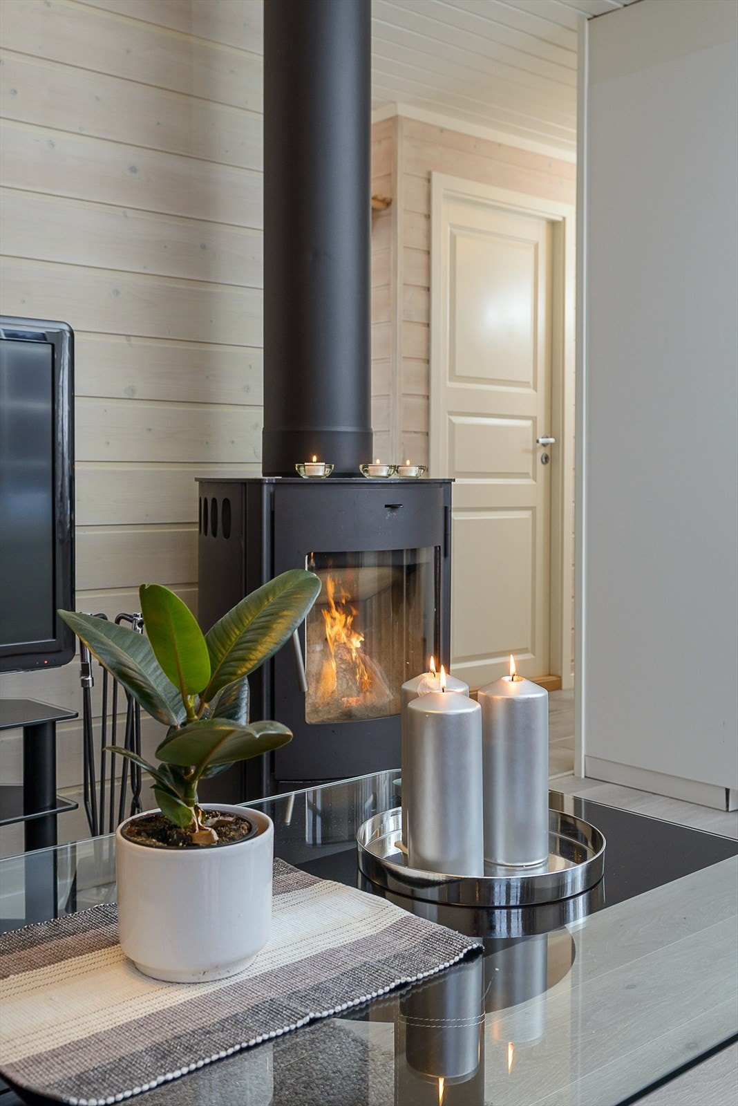 På kalde vinterkvelder kan man nyte kos og varme fra vedovnen, som er strategisk plassert mellom spisegruppe og sofa. Galleribilde