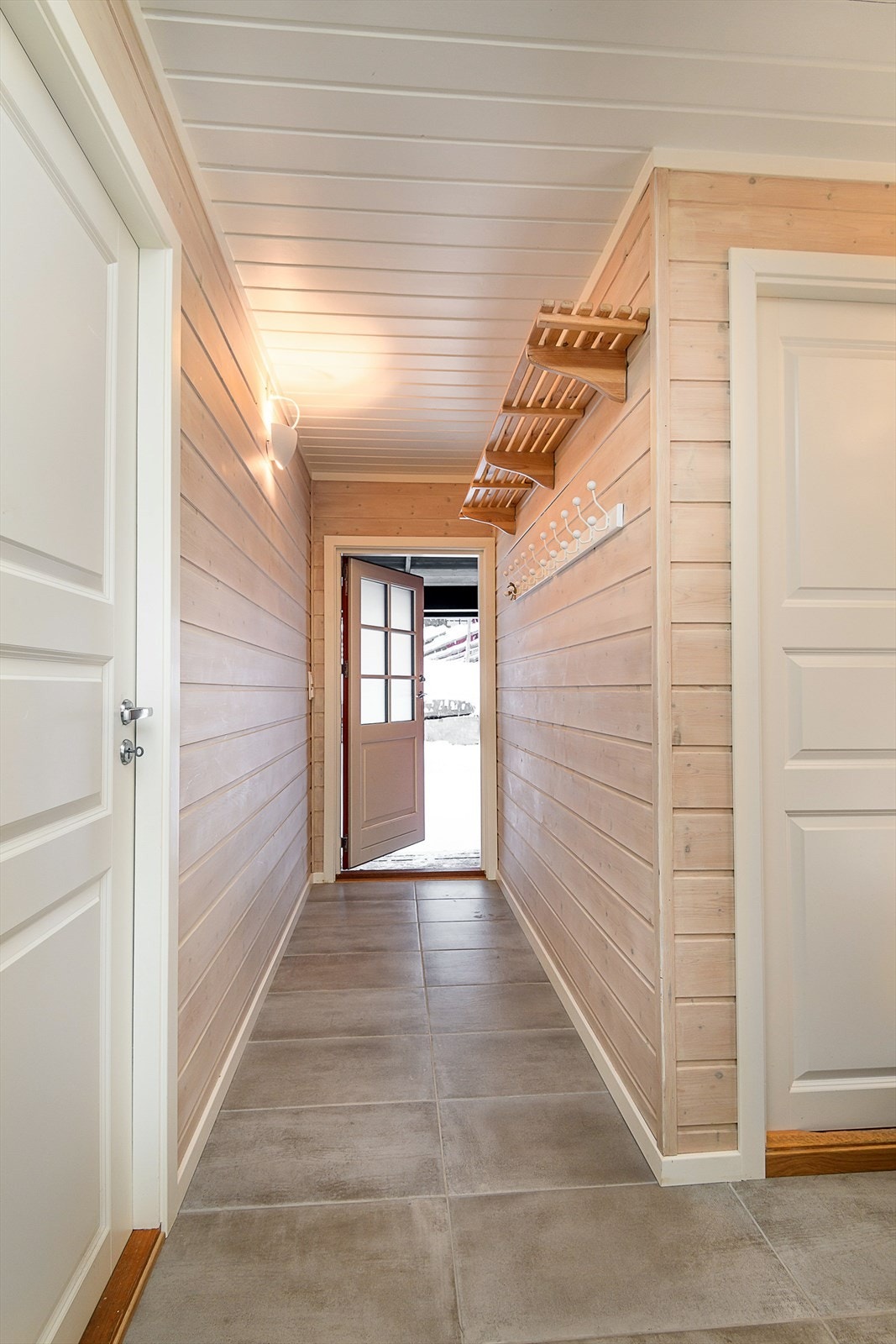 Velkommen inn! Fra overbygget inngangsparti kommer man inn i en lys og trivelig entré/gang med plass til å henge fra seg ytterklær. På gulvet er det fliser med varmekabler. Galleribilde
