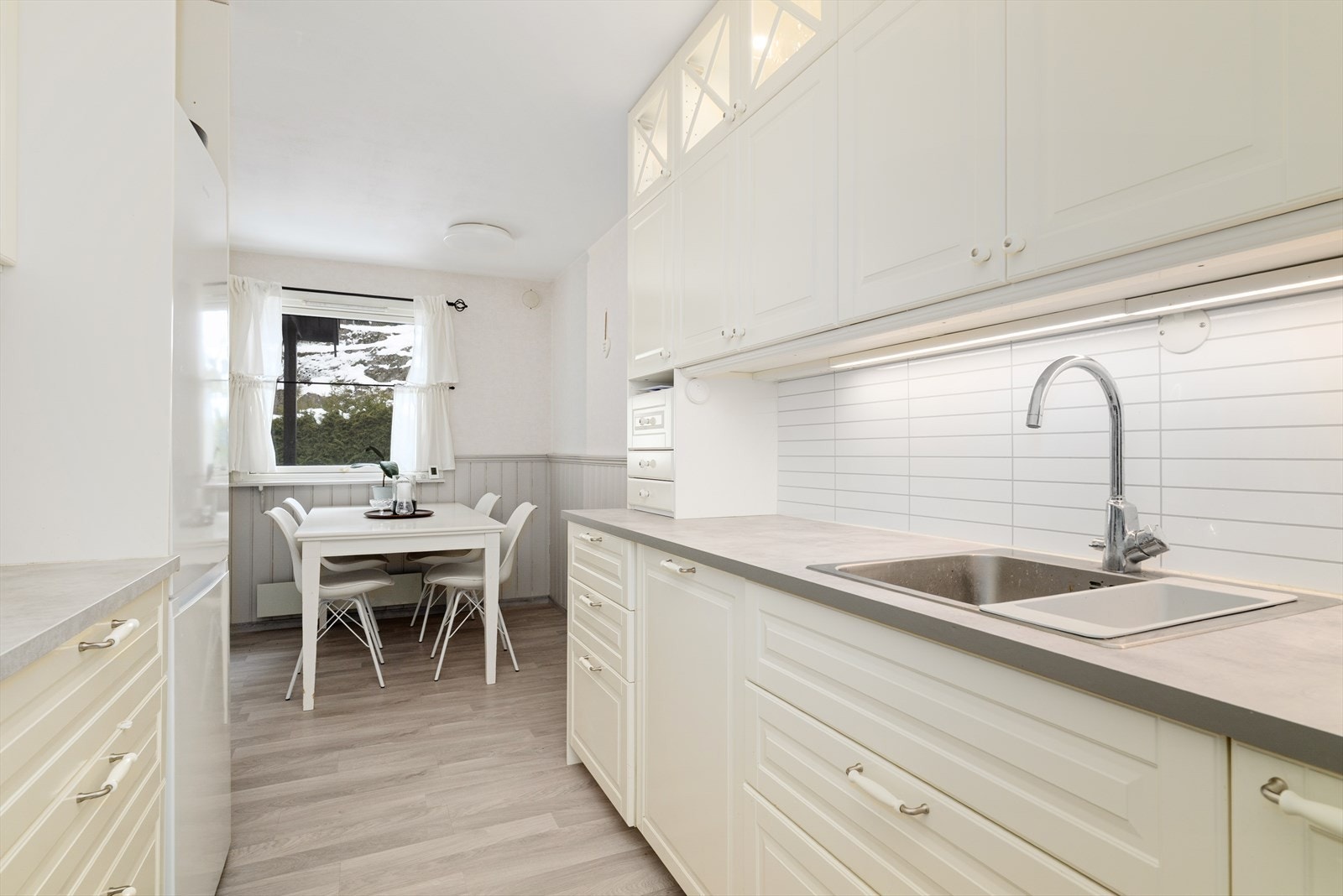 Lyst og pent kjøkken med takhøy kjøkkeninnredning type Ikea. Innredningen har integrert oppvaskmaskin og fine fronter i profilert utførelse. Galleribilde