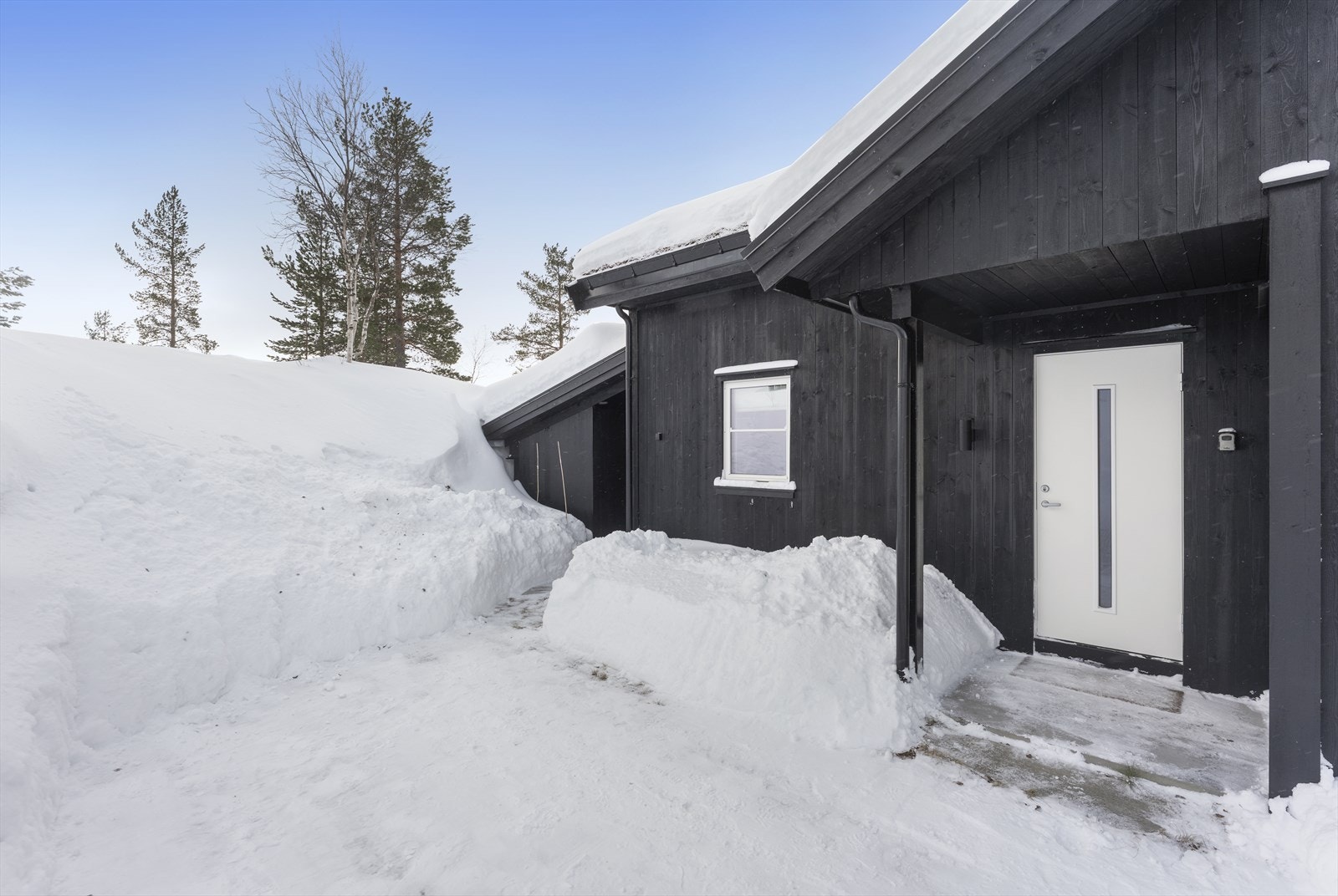 Inngangsparti med svalgang til overbygd uteplass og betongplatting foran hytten. Galleribilde