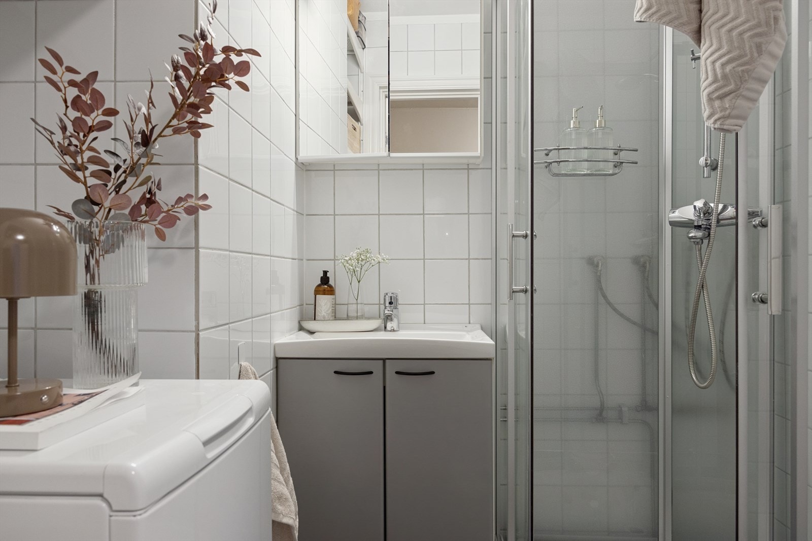 Baderommet er flislagt og innehar speil med overskap, servant med underskap og dusjkabinett. Galleribilde