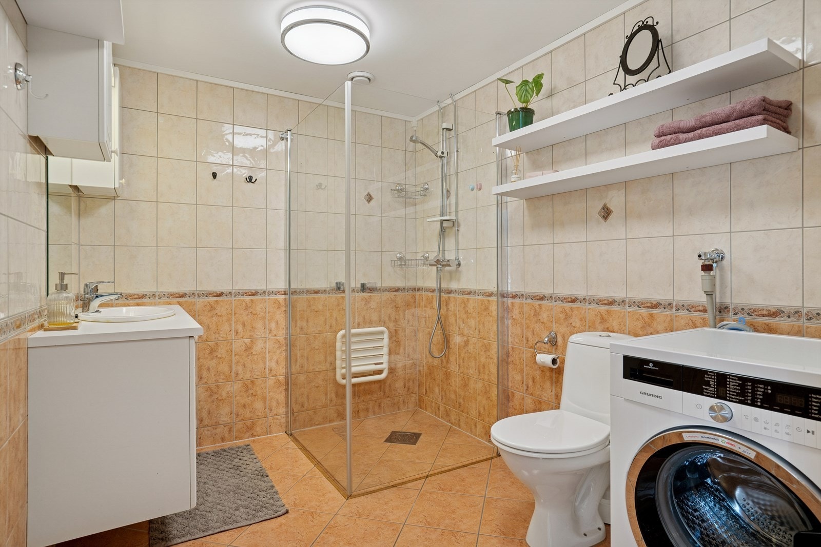 Rommet er utstyrt med dusjhjørne m/glassdører, toalett, baderomsinnredning og opplegg for vaskemaskin Galleribilde