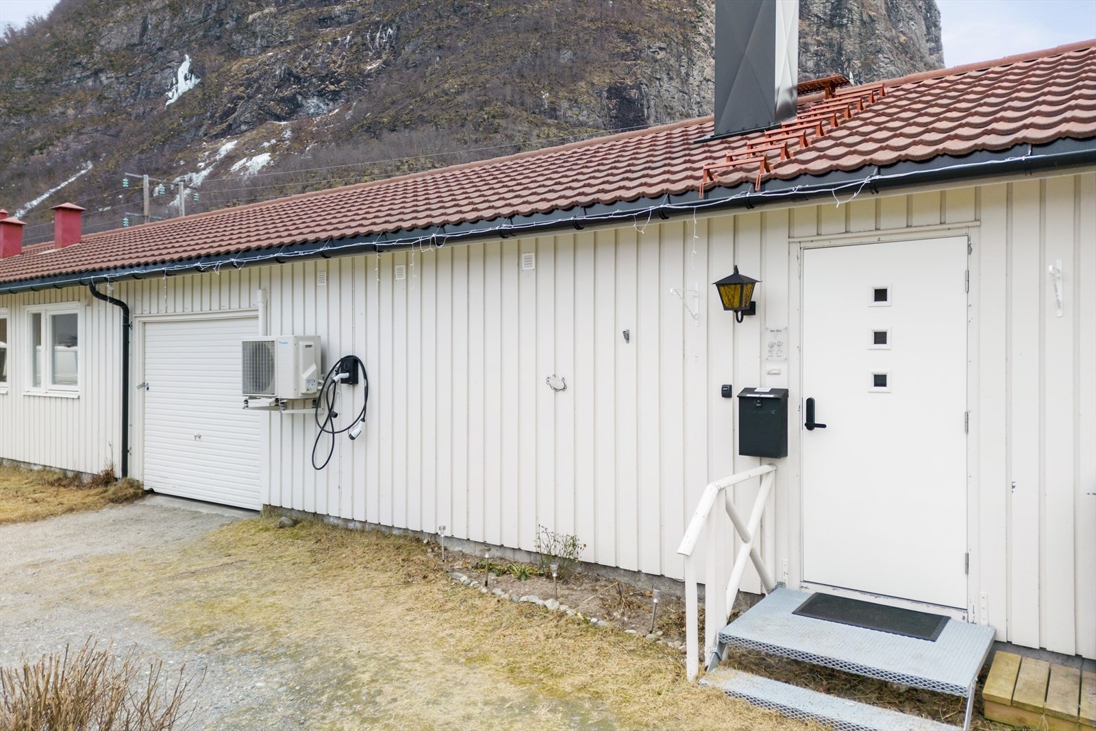 Garasjen er integrert i boligen med en hvit garasjeport. Galleribilde