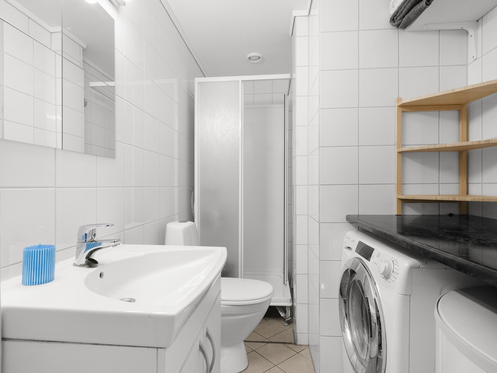 Baderom utstyrt med servant, dusjkabinett og opplegg for vaskemaskin. Galleribilde