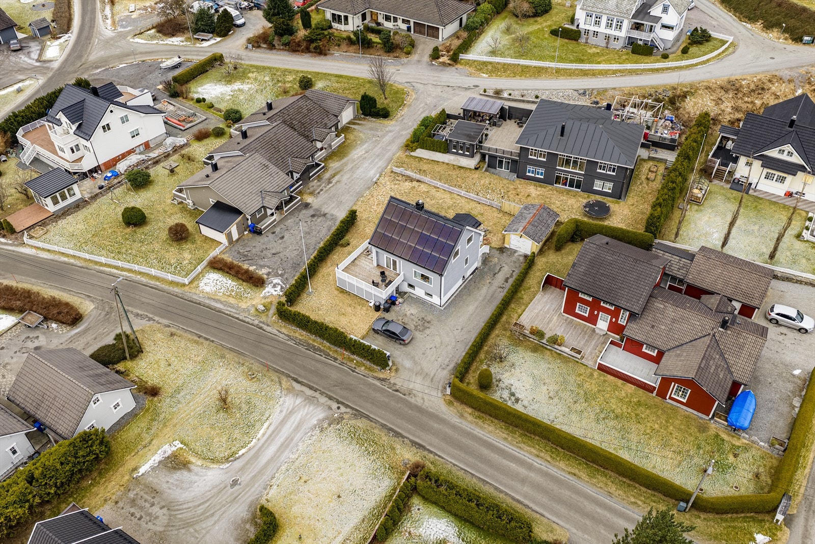 Flat, østvendt tomt er opparbeidet med betongplattinger, -trapp og -forstøtningsmurer, tregjerde, flaggstang, plen og beplanting | innkjørsel og parkeringsarealer med toppdekke av grus og singel Galleribilde