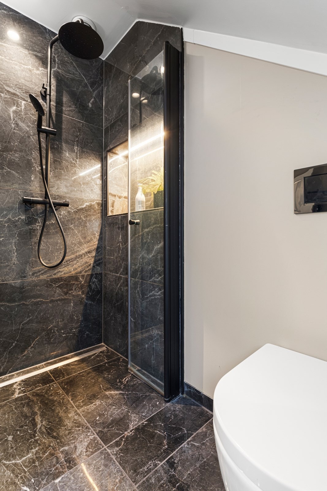 Bad på loft har flislagt gulv med sokkelflis og er utstyrt med baderomsinnredning, vegghengt wc, flislagt dusjnisje og badekar Galleribilde