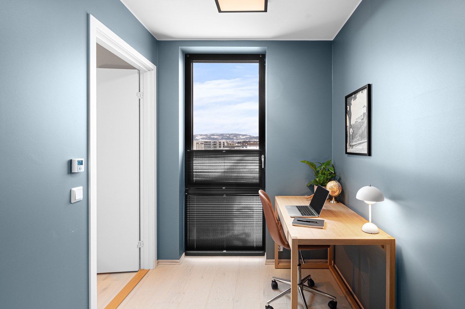 Soverommet er malt i en moderne farge og har et stort vindu som strekker seg fra tak til gulv og tilfører rommet rikelig med naturlig lys. Galleribilde