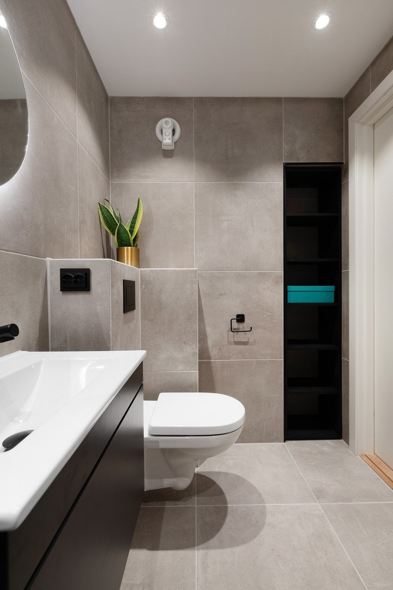 Badet inneholder veggmontert toalett, regnfallsdusj og servantinnredning med toppvask og skuff under Galleribilde