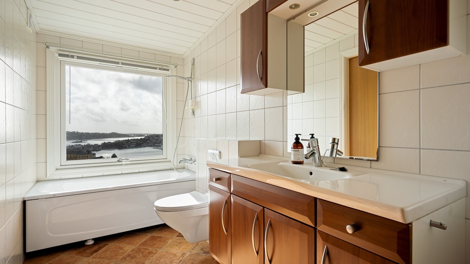 Lyst, flislagt bad med romslig innredning og badekar Galleribilde