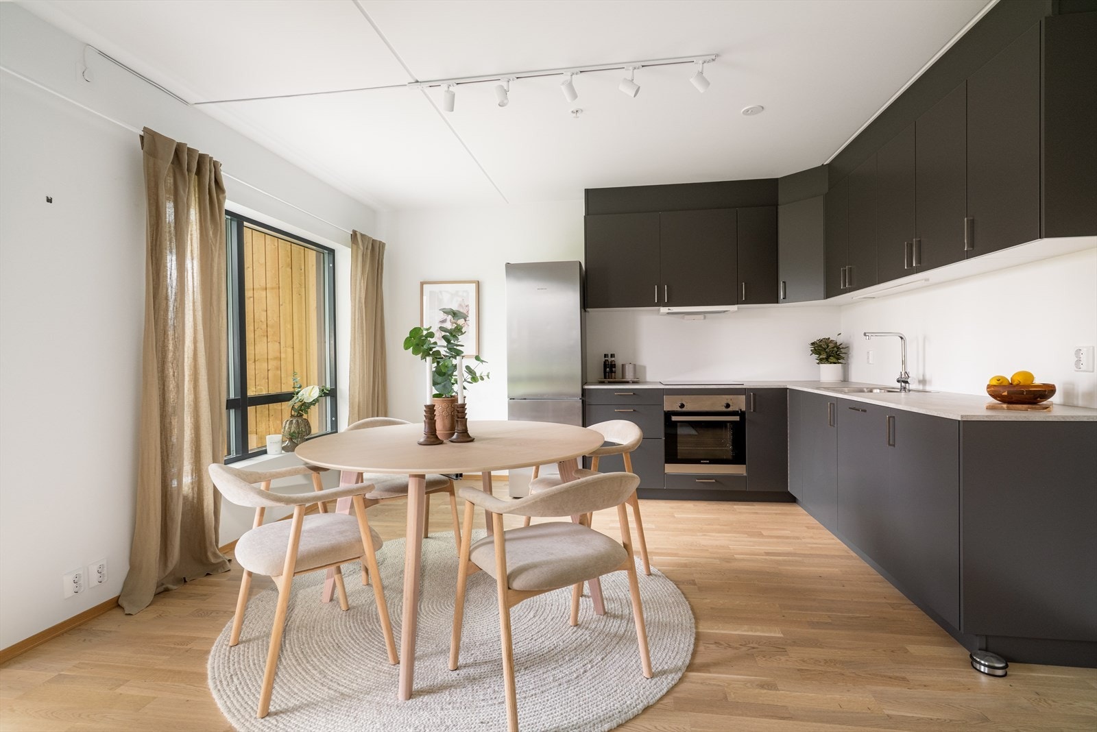 Kjøkkeninnredningen i mørk utførelse har slette fronter og går helt opp til taket. Her er det godt med skapplass, samt gode arbeidsflater på benkeplate i kompositt. Galleribilde